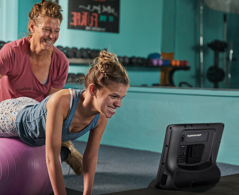 Femme utilisant son appareil de technologie d'assistance Tobii Dynavox TD I-Series à la salle de sport.